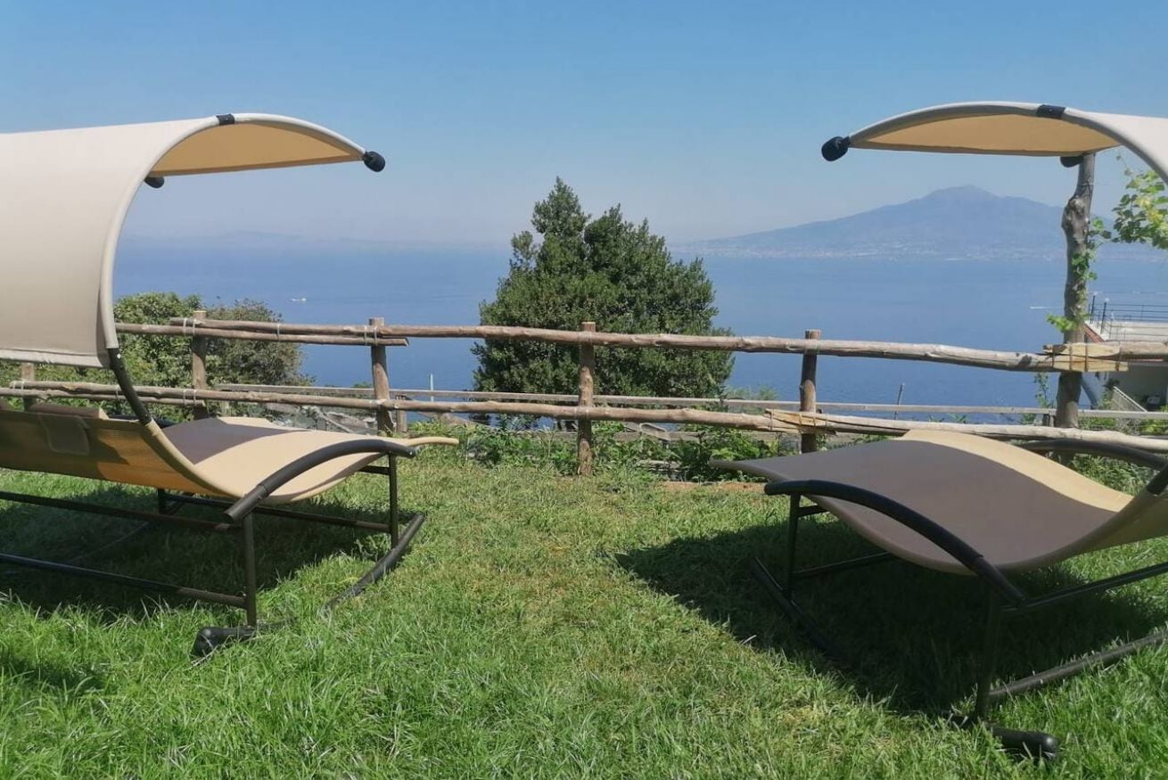 Two outdoor seating areas with a view of a body of water and a mountain in the background.