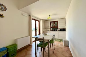 A compact kitchen with a dining area, a small window, and a ceiling fan.