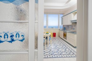 A kitchen with a view of the sea, a dining area with a table and chairs, and a patterned floor. - La Casa di Terry | Penthouse with Panoramic Terrace in the Heart of Sorrento (Sorrento)