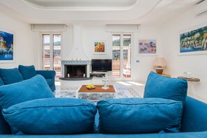 Ein Wohnzimmer mit Kamin, blauen Sofas und Kunstwerken an den Wänden.