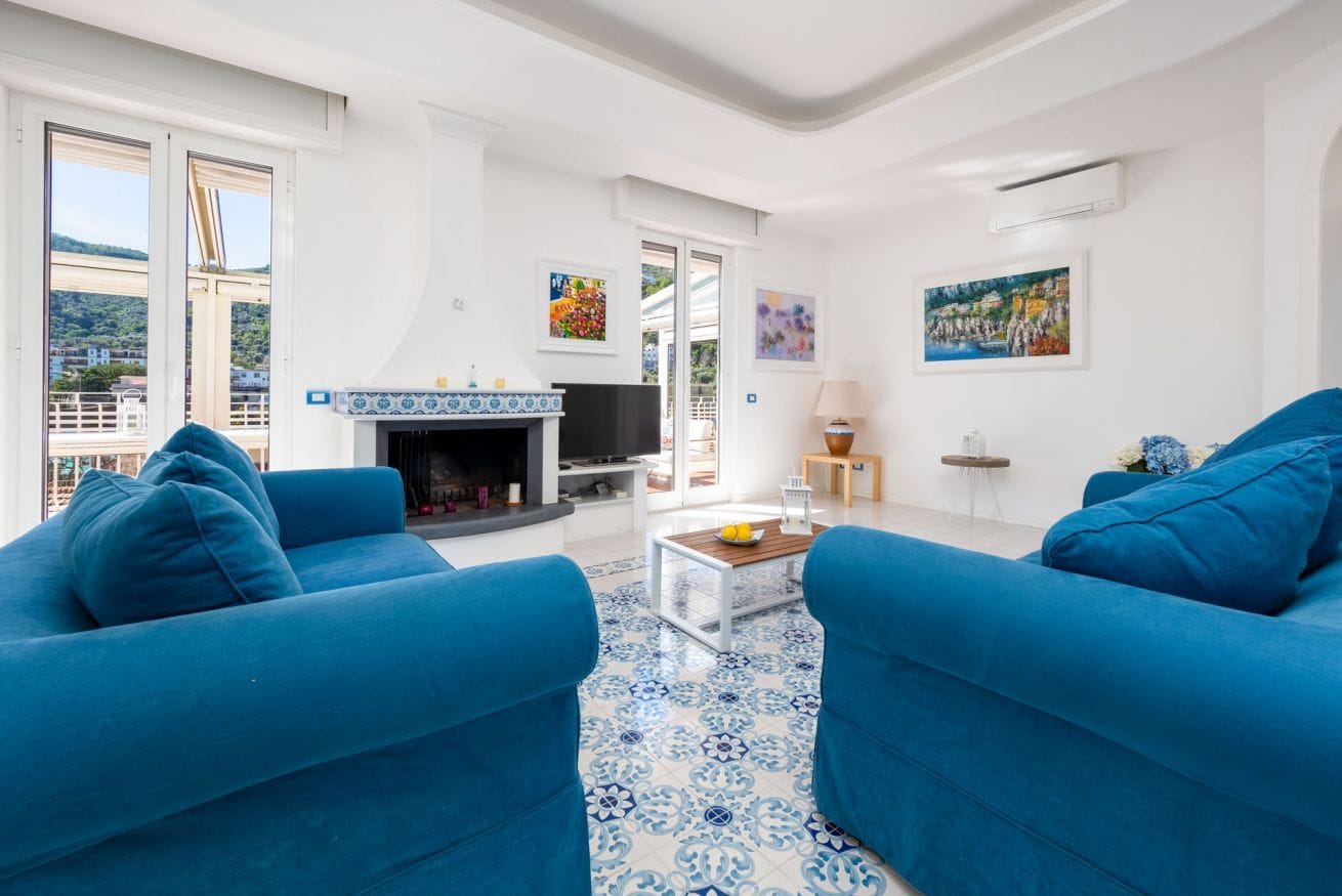A living room with blue sofas, a fireplace, and artwork on the walls.