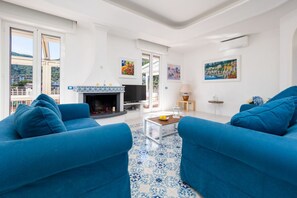 A living room with blue sofas, a fireplace, and artwork on the walls. - La Casa di Terry | Penthouse with Panoramic Terrace in the Heart of Sorrento (Sorrento)