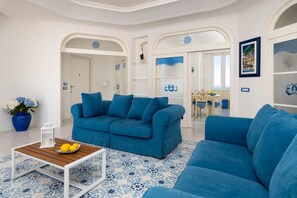 Ein Wohnzimmer mit einem blauen Sofa, einem Holztisch mit Zitronen und einem gemusterten Boden.
