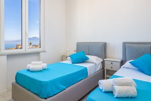 Ein Hotelzimmer mit zwei Betten, einem Fenster mit Blick und einem Nachttisch mit Lampe.