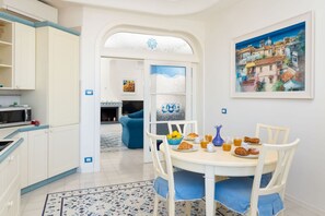 A kitchen with white cabinets, a dining table with chairs, and a breakfast setting. - La Casa di Terry | Penthouse with Panoramic Terrace in the Heart of Sorrento (Sorrento)
