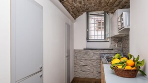 A narrow kitchen with a stone ceiling, a window, and a basket of oranges on the counter. - Casa Mirty – Comfort and the perfect location in the heart of the Sorrento Coast (Sant'Agnello)