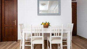 A dining area with a white table and chairs, a mirror above, and a basket of fruit on the table. - Casa Mirty – Comfort and the perfect location in the heart of the Sorrento Coast (Sant'Agnello)