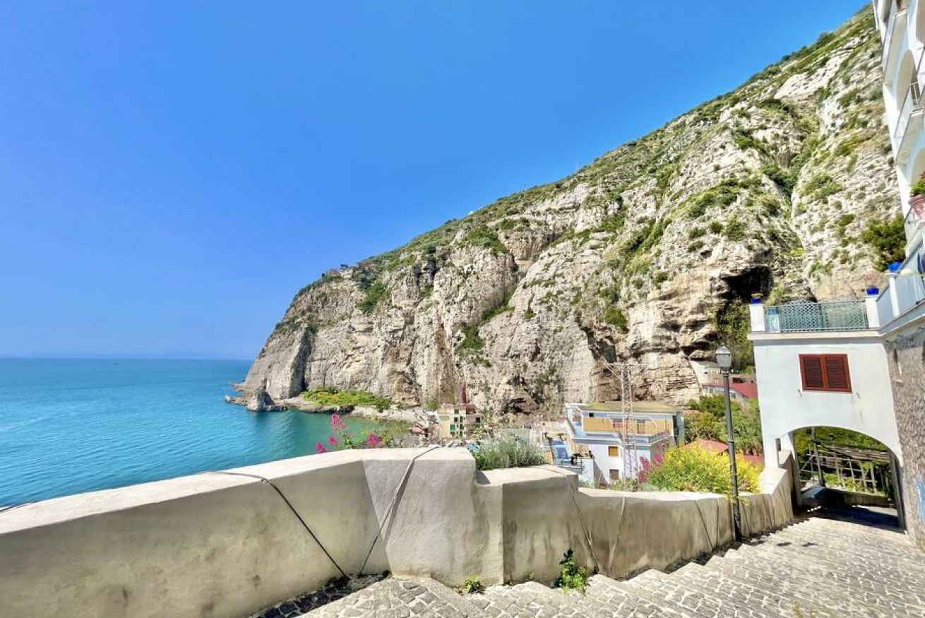 Un edificio sul lungomare con vista sul mare e su una scogliera rocciosa.