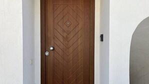 A wooden door with a geometric pattern, a round doorknob, and a wall-mounted light switch. - Casa Nicanto – Just Steps from the Sea, Between Peace and Comfort 🌊 (Meta)