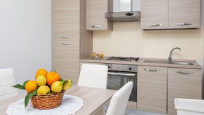 A modern kitchen with light wood cabinetry, a gas stove, and a sink.