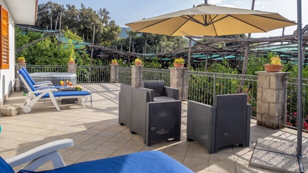 A patio with outdoor furniture, a large umbrella, and potted plants.