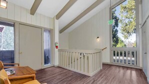 Une pièce avec un plancher en bois, une rambarde blanche, une porte et une fenêtre avec un panneau indiquant la sortie.