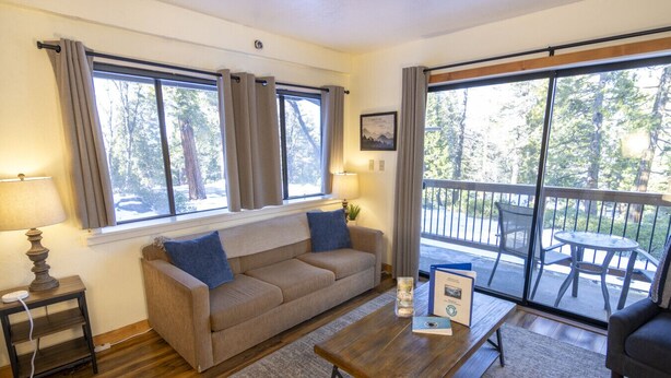 Un salon confortable avec un canapé, une table basse et un balcon équipé d’une table et de chaises.