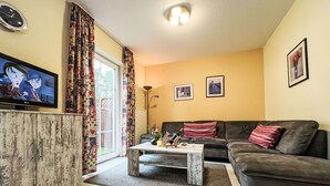 A living room with a sofa, a coffee table, a television, and a window with curtains. - Wonderful private villa for 6 guests with WIFI, TV, terrace and pets allowed (Waren)