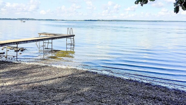 A wooden pier extending into calm water, surrounded by a pebbly shore. - Wonderful private villa for 6 guests with WIFI, TV, terrace and pets allowed (Waren)