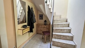 A staircase leading to an upper floor, a mirror with a coat rack, a small table with a lantern, and a wooden chair. - Wonderful private villa for 6 guests with WIFI, TV, terrace and pets allowed (Waren)