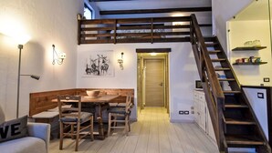 A cozy room with a wooden dining table, benches, a sofa, a staircase, and a door leading to another room. - Beautiful apartment for 4 people with WIFI, TV and balcony (Madesimo)