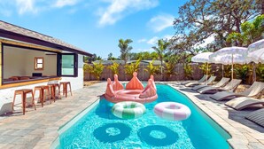 En pool med solstolar och uppblåsbara rutschkanor.