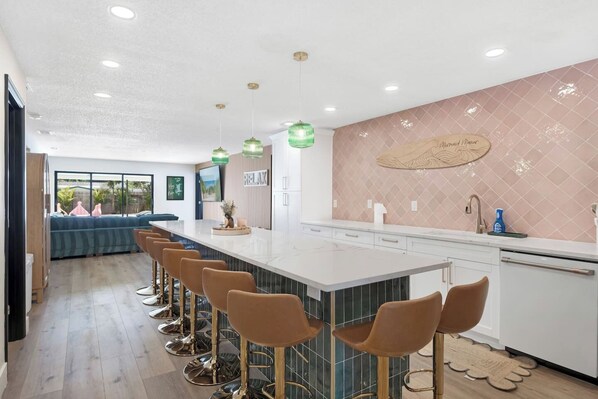A modern kitchen with a central island, bar stools, and pendant lighting.
