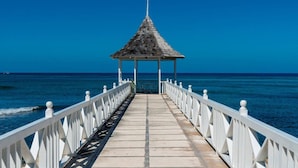 A pier leading to a gazebo with a clear view of the ocean.
