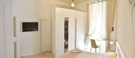 A bedroom with a bed, a TV, a desk, and a chair.