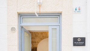 A building entrance with a glass door, a stone archway, and a sign indicating 'Vico Gelso'. - Palazzo Kapece  (Monopoli)