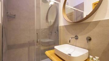 Une salle de bain moderne avec une douche à parois de verre, un lavabo sur pied et un miroir rond.
