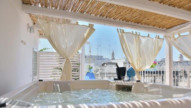 A hot tub with a city view, white walls, and a bamboo ceiling. - Palazzo Kapece  (Monopoli)