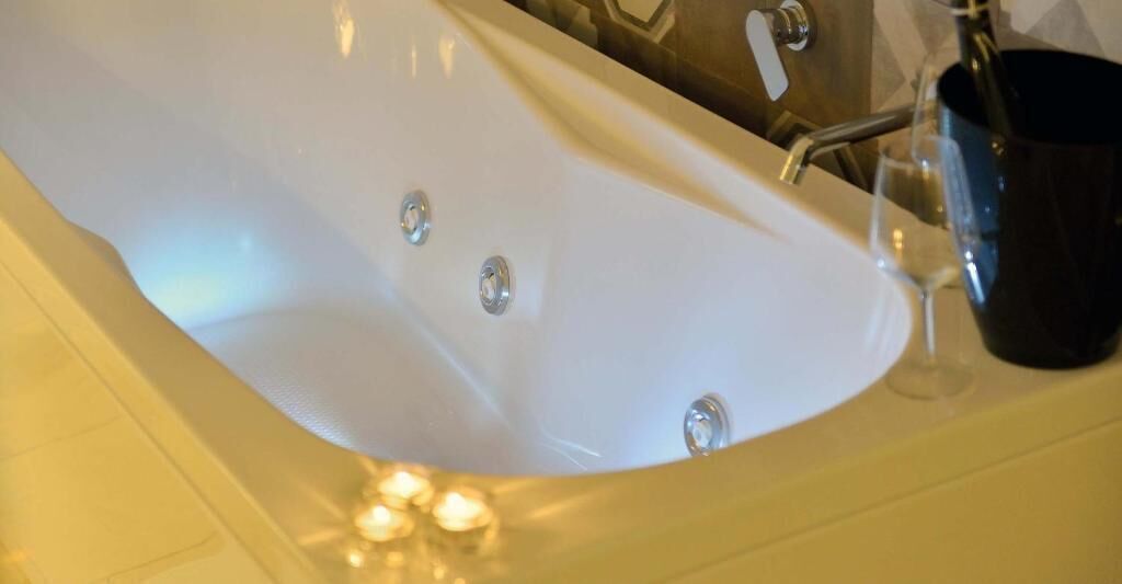 Eine Wanne mit Wasserhahn und einem Glas.