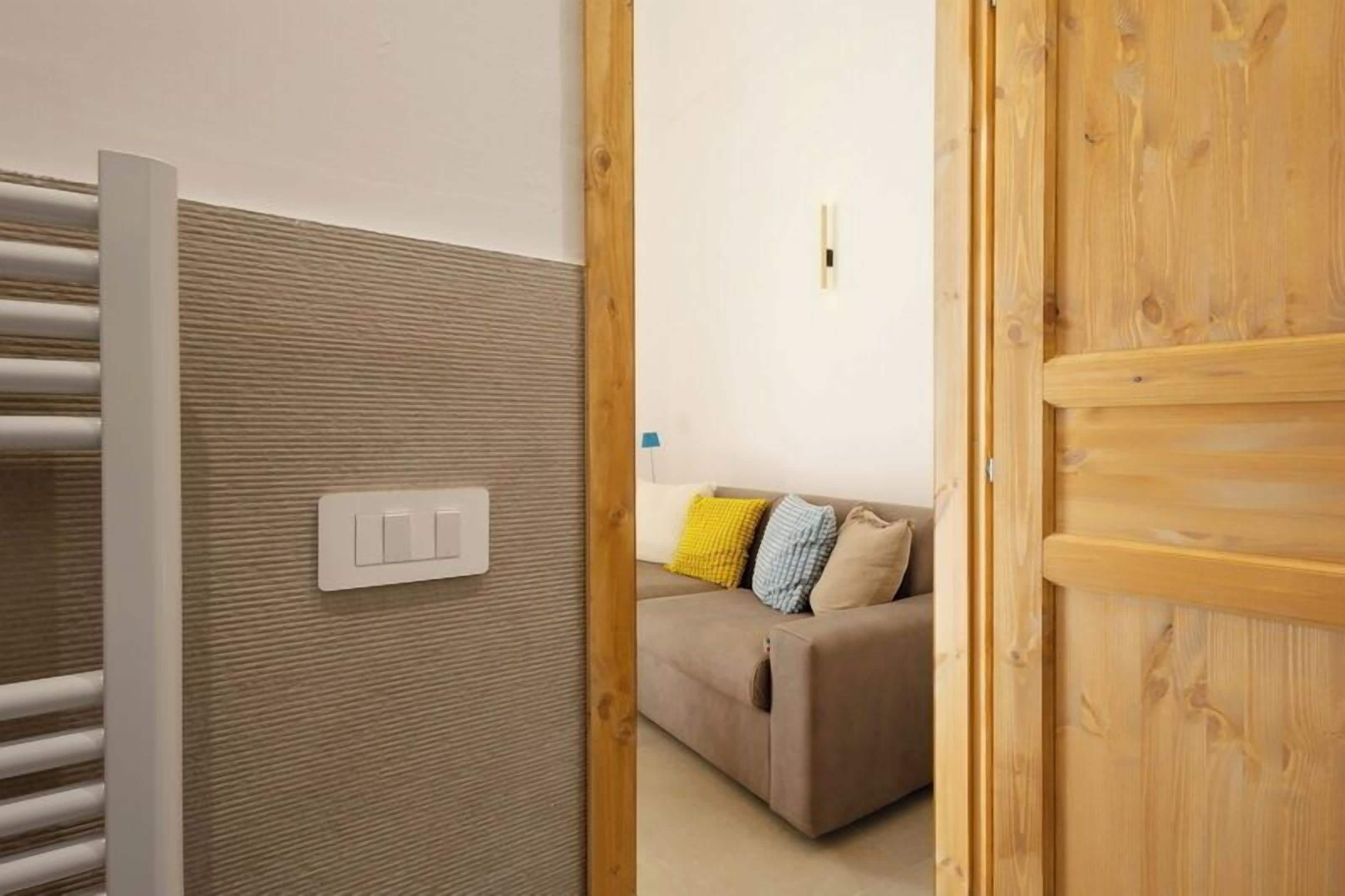 A room with a radiator, a wall-mounted light switch, and a wooden door.