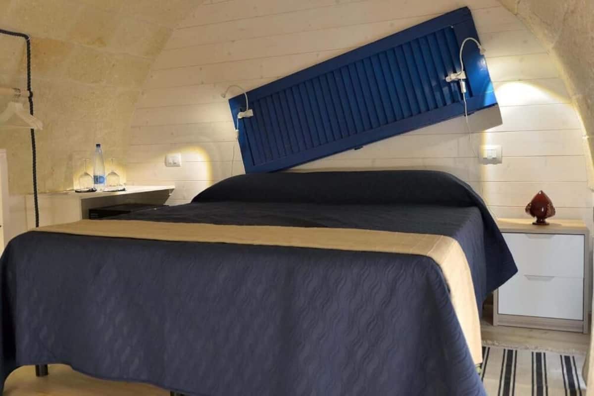 A room with a bed, a nightstand, a lamp, and a blue headboard.