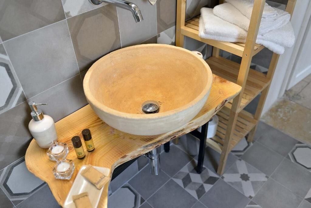 A bathroom with a large, round, beige ceramic sink mounted on a wooden countertop.