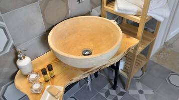 Ein Badezimmer mit einem großen, runden, beige gefärbten Keramikbecken auf einer Holzauslage.