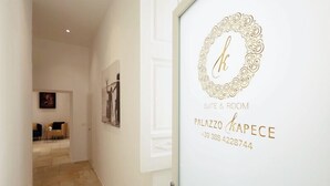 A hallway with a door labeled "Palazzo Kapice Suite & Room" and a contact number. - Palazzo Kapece  (Monopoli)
