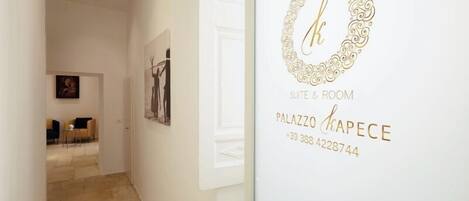 A hallway with a door labeled "Palazzo Kapice Suite & Room" and a contact number.