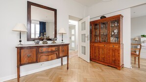 Una habitación con un aparador de madera, un espejo grande y un mueble con puerta de cristal.