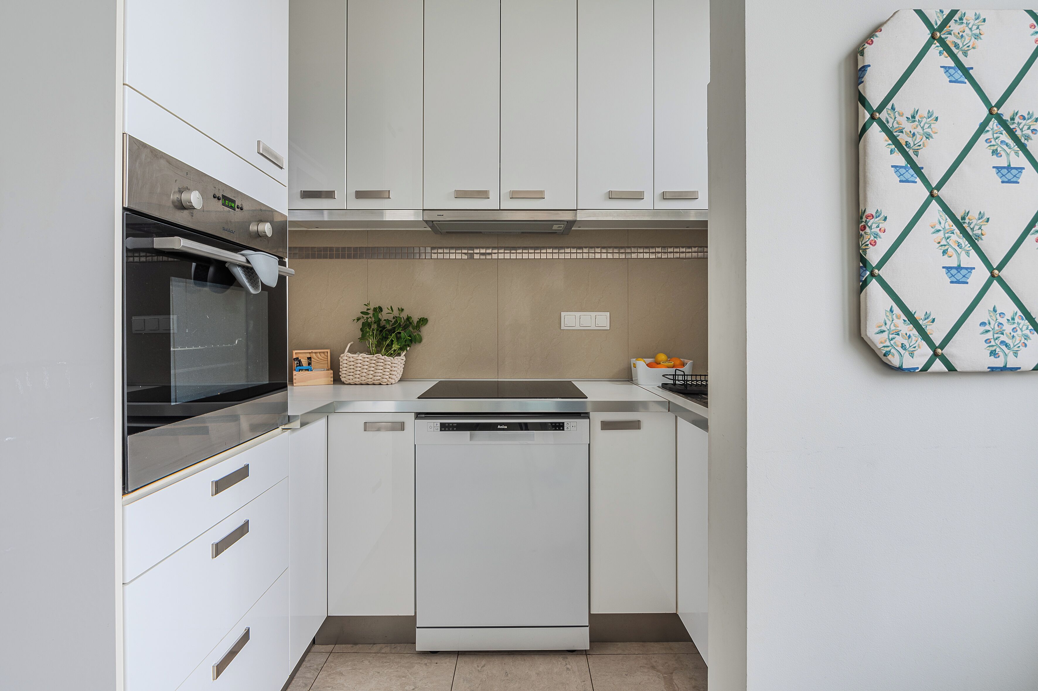 A modern kitchen with white cabinets, a built-in oven, and a dishwasher.