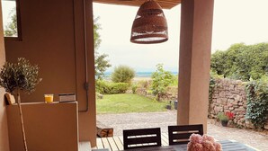 An outdoor patio with a wooden table, chairs, a potted plant, and a hanging light fixture. - Gîte Origin route des vins d'Alsace (Gueberschwihr)