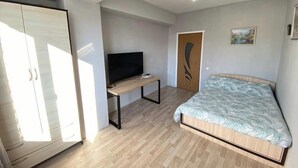 Une chambre à coucher avec un lit, un téléviseur posé sur un bureau, une armoire et une porte.