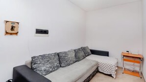 Une petite pièce au mobilier minimaliste, comprenant un canapé, une petite table et une étagère fixée au mur.