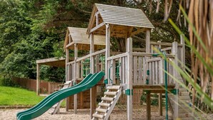 Una estructura de juegos de madera con toboganes y elementos para escalar.