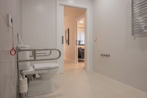 Et moderne badeværelse med toilet, gelænder og håndklæderække.