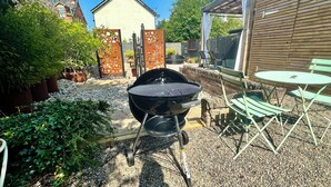Ein Garten mit Grill, Sitzgelegenheit und einem Gartenbereich.
