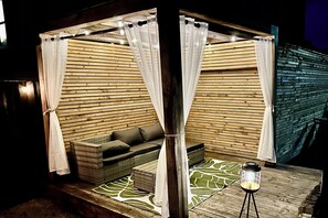 A cozy outdoor seating area with a cushioned bench, a small table, and a lantern.