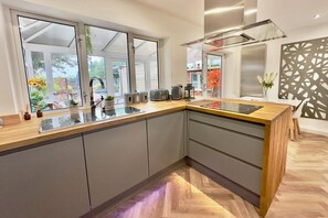 A modern kitchen with a large island, built-in appliances, and a view of the garden through large windows.