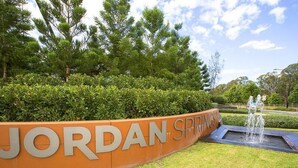 A sign for Jordan Springs with a water feature in the foreground. - Family and Group Holiday Home Sleeps 13 Near Western Sydney Airport, Penrith (Jordan Springs)