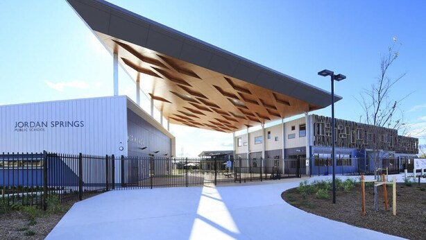 A modern public school building with a distinctive sloped roof and a covered entrance area. - Family and Group Holiday Home Sleeps 13 Near Western Sydney Airport, Penrith (Jordan Springs)