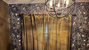 Un dormitorio con una cama grande, dos mesitas de noche, una araña y papel tapiz estampado.