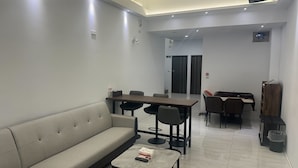 A modern hotel room with a sofa, a small table with a remote control, a wooden desk, and a chair. - New One Villa (Hengchun)
