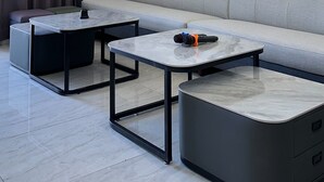 A modern living room with a grey sofa, two marble-topped coffee tables, a black ottoman, and an air conditioning unit mounted on the wall. - New One Villa (Hengchun)